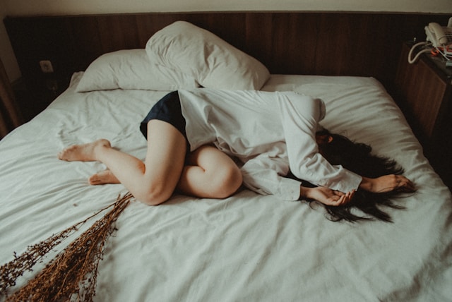 ベッドにうずくまる女性