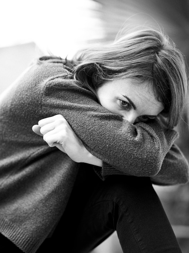 膝を抱え込む絶望的な表情の女性