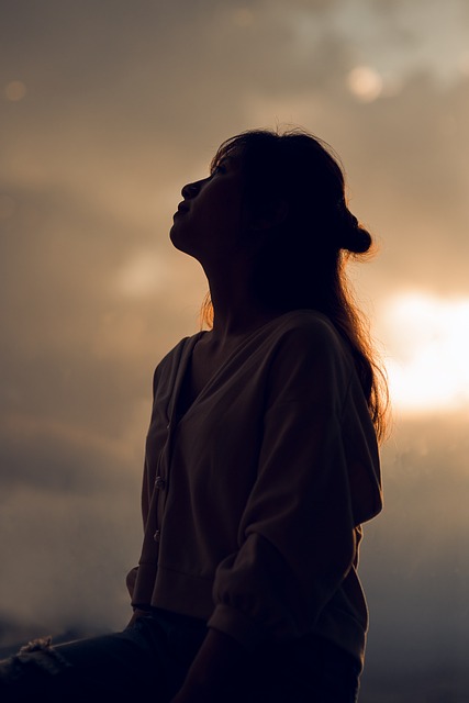 夕日を背景に呆然と空を見上げる女性