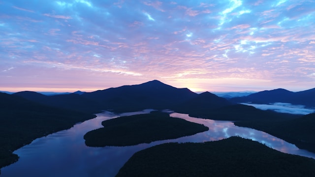 逆光で暗い山々と淡い青とピンクの空とそれを映す川。